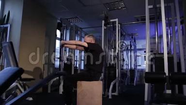 一个同龄的人在<strong>健身</strong>房里为肘部和背部做关节体操。 脊柱弯曲。 复制空间。